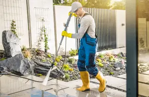 Worker using power washing to clean the steps of a house
