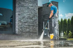 Worker cleaning pavement with pressure washing technique